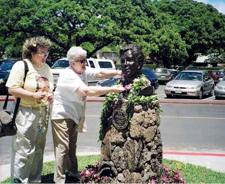 Annette Nixon and Ennis Dudley placing their leis on Jack's bust.